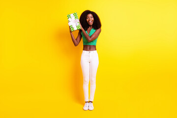 Full length body size photo funky girl smiling trying to guess what inside gift box isolated vivid yellow color background