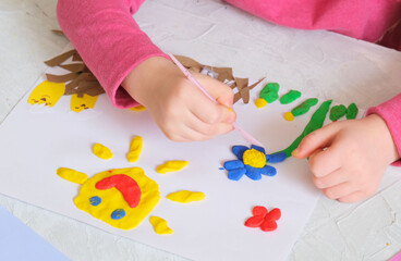 Child making spring card from colorful paper and clay. Handmade. Project of children's creativity, handicrafts, crafts for kids.