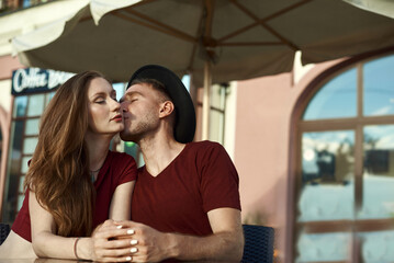 Summer holidays, love and tourism concept. Romantic happy couple kissing in the cafe outdoor in summer