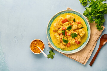Chicken tikka masala. Traditional of indian cuisine curry and ingredients on dark background. Curry, lime, ginger, cilantro, chili, rice, herbs and spices. Top view with copy space.