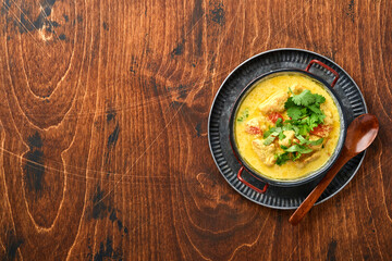 Chicken tikka masala. Traditional of indian cuisine curry and ingredients on dark background. Curry, lime, ginger, cilantro, chili, rice, herbs and spices. Top view with copy space.