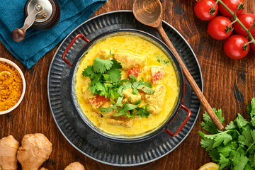 Chicken tikka masala. Traditional of indian cuisine curry and ingredients on dark background. Curry, lime, ginger, cilantro, chili, rice, herbs and spices. Top view with copy space.