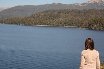 Fototapeta na wymiar woman with her back turned on the shores of a pensive lake with mountains