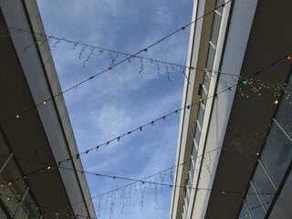 Fototapeta premium 建物の間にデコレーションされたカラフルな電飾、快晴
