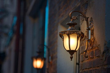Lantern with yellow warm light on facade of building. Twilight on city street, building...