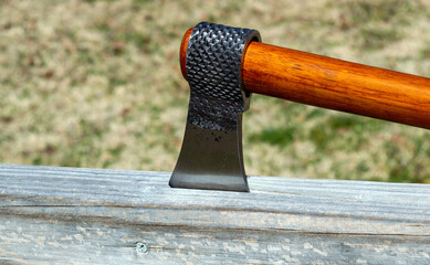 The razor sharp tomahawk has been embeded in the plank of wood. Bokeh effect.