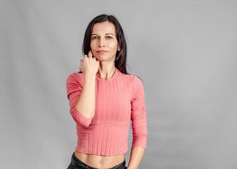 Portrait of slender middle-aged woman in a short sweater looking at the camera. Hand supports face