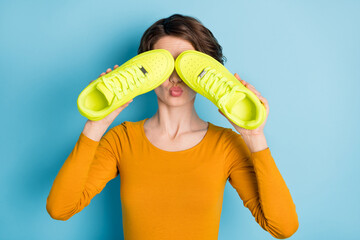Photo of nice flirty brunette lady cover face by sneakers wear yellow shirt isolated in vivid blue...