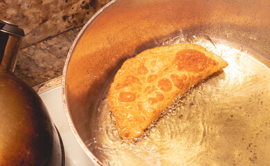 Pastel, Comida brasileira. Um pastel fritando no óleo  em uma panela grande. O pastel é um tipo de alimento recheado com massa de farinha de trigo frito no óleo.