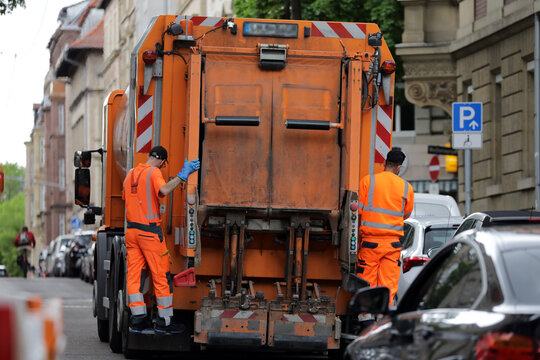 m&uuml;llwagen auf tour mit zwei m&uuml;llm&auml;nner in der stadt
