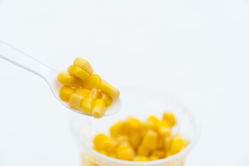 Tinned corn on a spoon isolated on white