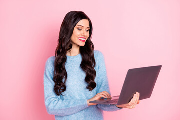 Portrait of pretty positive person look netbook beaming smile wear pullover isolated on pink color background