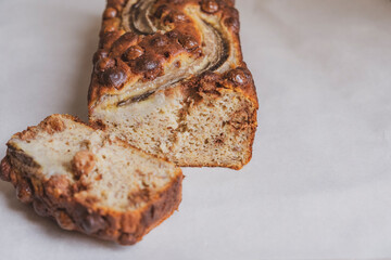 Delicious freshly baked banana bread with chocolate chips on white tablecloth background. Sweet vegan gluten free food, from above. Homemade baked goods.
