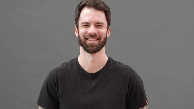 The Smiling Man Positively Nodding His Head While Standing In A Gray Studio