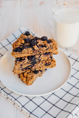 Stack of homemade oatmeal scones with berries stacked on white plate and glass of plant based milk. Vegan sweet baked food. Gluten free pastry. Healthy breakfast.