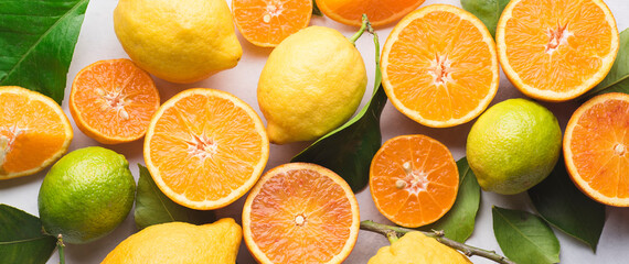 Citrus fruits background, banner. Oranges, oranges Tarocco, lime, lemon and mandarins with green leaves.  Healthy food and drinks concept, flat lay, copy space. Organic citrus fruits