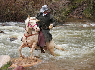 cowboy on white horse crossing dangerous river