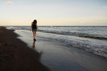 A young woman walks along the seashore at sunset. High quality photo