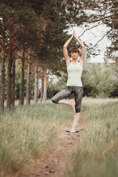 Sporty woman practicing yoga, stretching and relaxation in park outdoors, fitness in nature