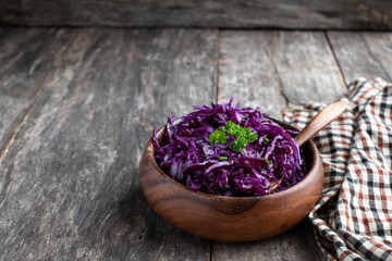 Red cabbage salad in wooden bowl on rustic wooden table