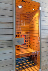view into a wooden infrared cabin with glowing heating elements and closed glass door