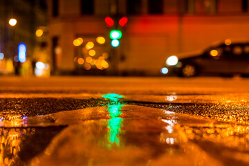 Nights lights of the big city, the night avenue with a car standing at the traffic lights. Close up...