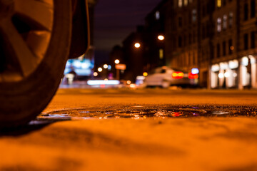 Nights lights of the big city, the night street with a passing car. Close up view from the level of...