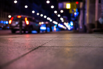 Nights lights of the big city, the car parked at roadside. Close up view from the level of the sidewalk