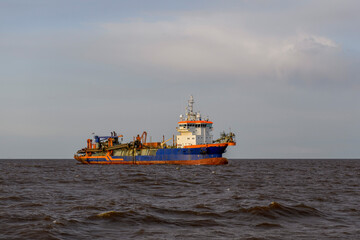 Hopper dredger at sea. Vessel engaged in dredging. Construction Marine offshore works. Dam building, crane, barge, dredger.