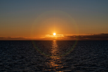Naklejka premium Beautiful sunset on sky with clouds at sea. Golden hour lighting.