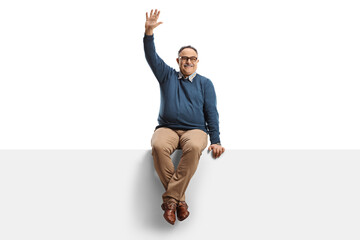 Mature man sitting on a blank billboard and waving