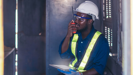 Industry engine technicians are talking with walkie talkie and using the tablet to research engine...