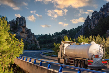 Tank truck with dangerous goods circulating on a viaduct between rocky mountains.