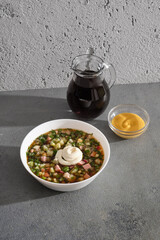 plate of cold okroshka soup with kvass on a gray concrete background with space for text and hard...