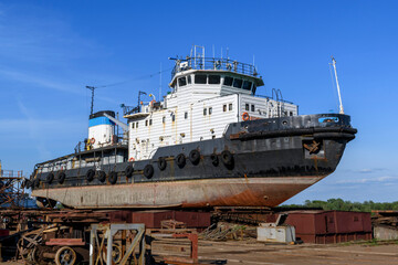 Tug vessel ashore on ship repairing yard. Summer time.