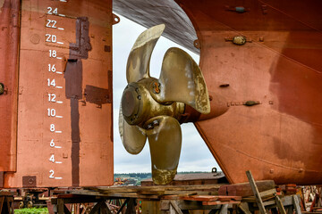 Variable pitch propeller and rudder. Cargo vessel ashore on ship repairing yard.