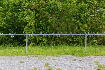 Empty bike racks for bikes on a gravel path in front of green forest, during the day, without people, in nature you can still find free parking spaces