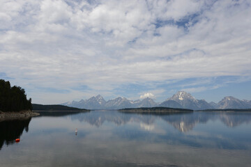 Scenic view of a lake with mountains in the background and lake reflections in Grand Teton National Park on a cloudy day