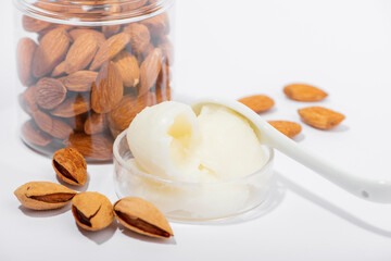 Sweet almond butter and natural almonds on white background.