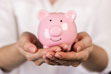 Piggy bank in hand on light background, space for text. Finance, saving money. Business to success and saving for retirement concept