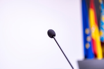 microphone on white background next to international flags (spain, europe), prepared for speech (talk, conference, statement)