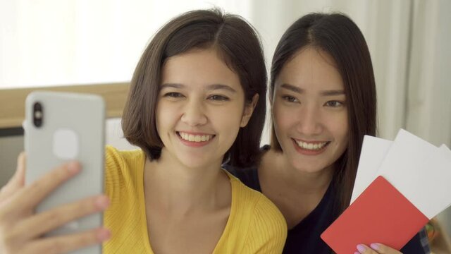 4K Young beautiful Asian couple love friend woman hold passport take picture selfie by smartphone on bed when summer trip which smiling and felling happy, LGBT woman love Travelling vacation trip