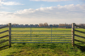 Fototapeta na wymiar Countryside landscape with flat and low land, Typical Dutch polder and water land, Green meadow and wooden fence, Small canal or ditch on the field along the road, Noord Holland, Netherlands.