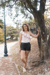 Portrait of a young Hispanic female posing in the park by the flowering tree