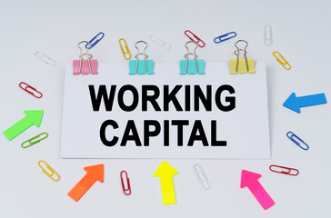 On the table there are paper clips and directional arrows, a sign that says - Working Capital