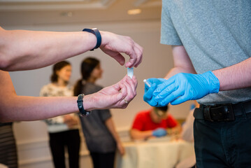 A pair of hands without gloves holds a vial near a pair of hands with blue latex gloves during a school chemistry experiment.