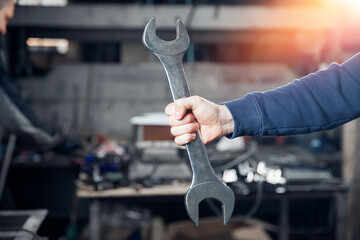 Wrench in hands of professional turner man metal working on factory