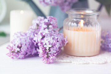 Obraz na płótnie Canvas Beautiful composition with fresh violet lilac bouquet in watering and candles. Cozy atmosphere. Greeting card for Saint Valentine's Day, 8 march, Women's day, Mother's day. White background