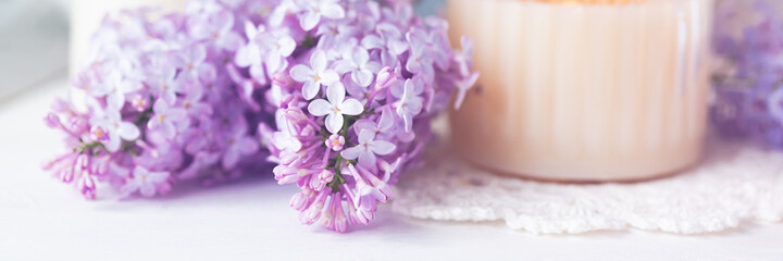 Beautiful composition with fresh violet lilac bouquet in watering and candles. Cozy atmosphere. Greeting card for Saint Valentine's Day, 8 march, Women's day, Mother's day. White background banner