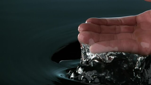 Super slow motion of man hand with splashing water. Filmed on high speed cinema camera, 1000fps.